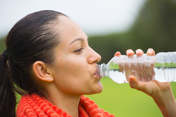 Young exercising woman drinking water