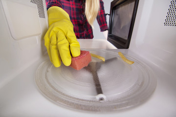 Woman in protective gloves wash inside the microwave