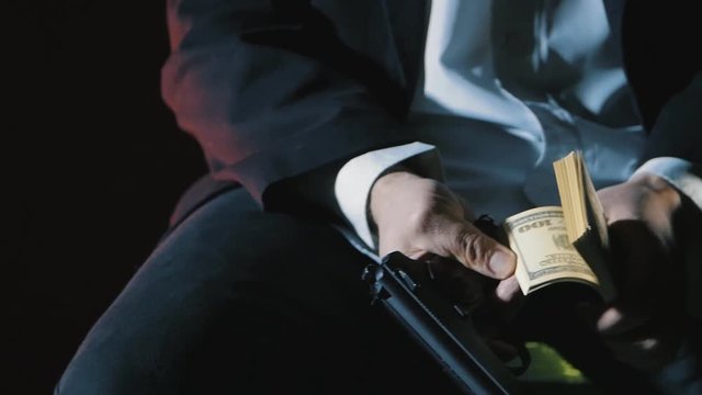 close-up hands of a dangerous man with a gun counts the money. Dirty Money Mafia.