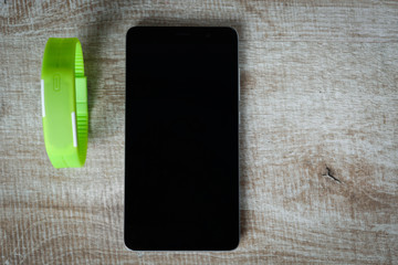 fitness bracelet with a smartphone on a wooden background. sport. fitness.