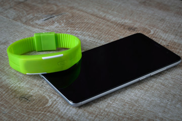 fitness bracelet with a smartphone on a wooden background. sport. fitness.