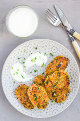 Vegetarian quinoa, carrot, coriander and green onion fritters served with yogurt on plate, vertical, top view