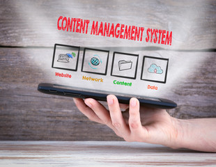 Content Management System concept. Tablet computer in the hand. Old wooden background.