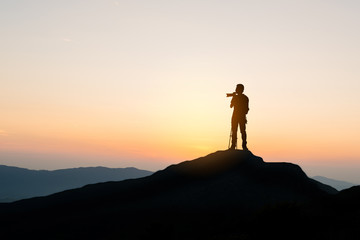 photographer on top of mountain at sunset background