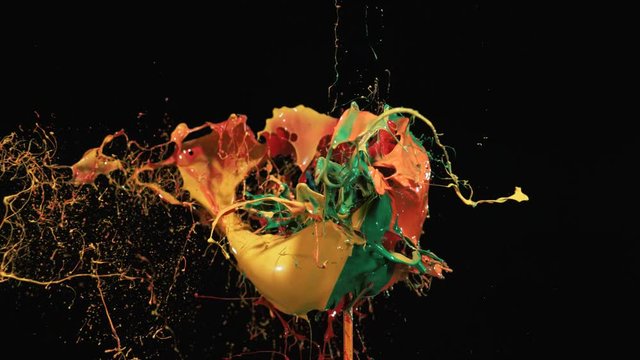 Orange, yellow, green and red paint explodes and splashes. Shot with high speed camera, phantom flex 4K. Slow Motion.