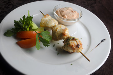 Kebab skewers with vegetables on a white plate in a restaurant