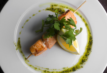 Kebab skewers trout with vegetables on a white plate in a restaurant