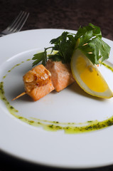 Kebab skewers trout with vegetables on a white plate in a restaurant