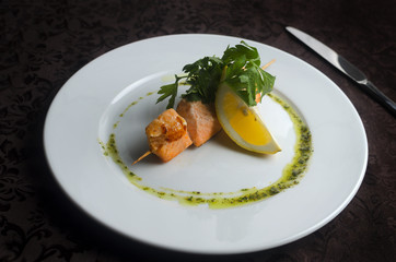 Kebab skewers trout with vegetables on a white plate in a restaurant