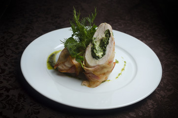 Roll chicken in bacon on a white plate in a restaurant