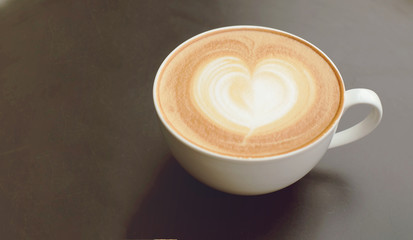 a cup of latte coffee with roasted coffee bean on wooden table background.