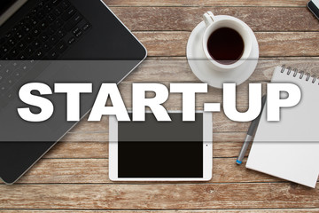 Naklejka premium Tablet on desktop with start-up text.