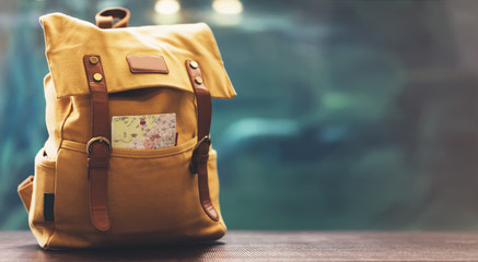 Hipster yellow backpack and map closeup. View from front tourist traveler bag on background blue...