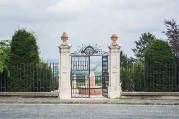 The gate to the garden on the top of te hill on a cloudy day with the panorama of fields, Pannonhalma Abbey, Gyor, Hungary.