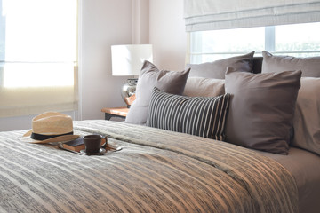 stylish bedroom interior design with striped pillows on bed and decorative table lamp.