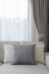 Pillows setting on couch with dark gray curtain in background