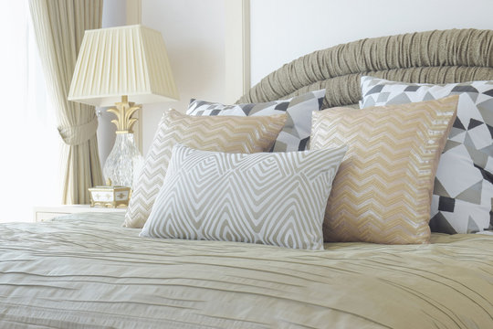 Golden and silver pillows setting on bed with luxury style interior bedroom