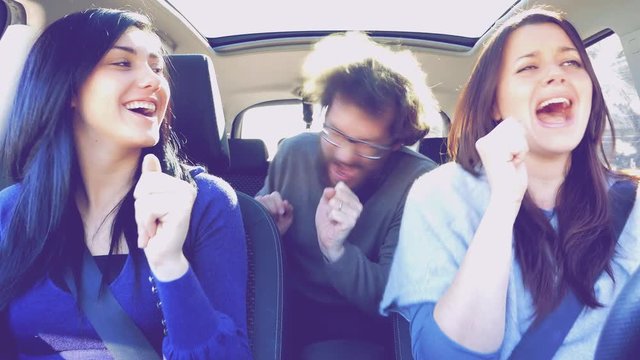 Three happy people in car driving dancing and singing like crazy retro style funny