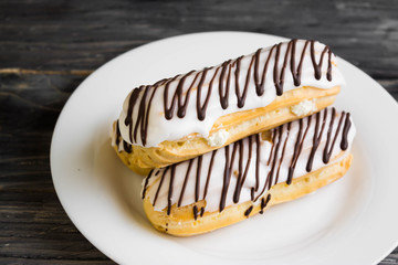 Eclairs in white glaze on a white plate. Delicious dessert.