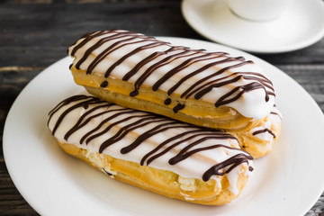 Eclairs in white glaze on a white plate. Delicious dessert.