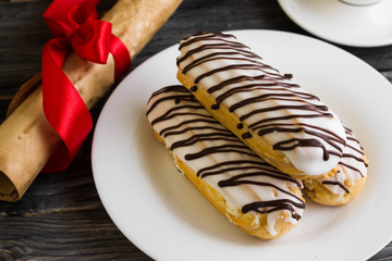 Eclairs in white glaze on a white plate. Delicious dessert.