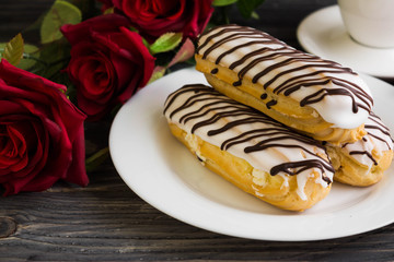 Eclairs in white glaze on a white plate. Delicious dessert.