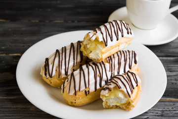 Eclairs in white glaze on a white plate. Delicious dessert.