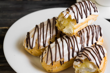 Eclairs in white glaze on a white plate. Delicious dessert.