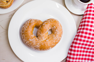 Pretzel in sugar on a marble table. Tasty dessert.