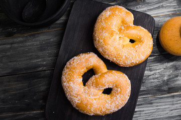 Pretzel in sugar on a wooden background in rustic style. Tasty dessert.
