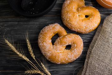 Pretzel in sugar on a wooden background in rustic style. Tasty dessert.