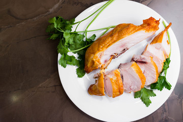 Smoked chicken breast on a marble table and ingredients. A delicious dish.
