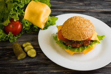 Hamburger on a wooden table in rustic style and ingredients