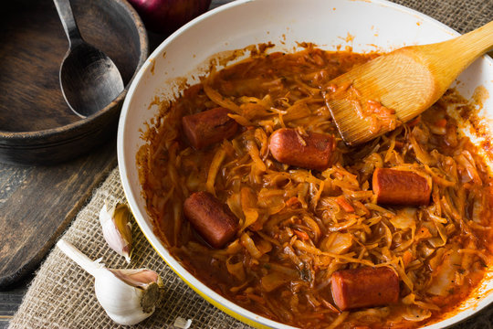 Bigus with sausages in a frying pan on a wooden background in rustic style