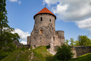 Fototapeta na wymiar Big tower and beautiful ruins of ancient Livonian castle in old town of Cesis, Latvia. Greenery and summer daytime.