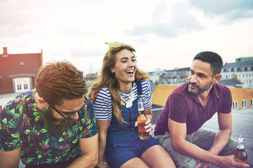 Laughing group of barefoot friends drinking beer