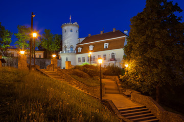 Fototapeta na wymiar New white castle in old town of Cesis, Latvia. Part of ancient Livonian castle ruins. Greenery and summer night.