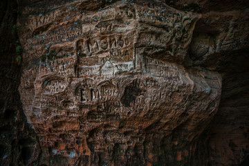 Natural cave in sandstone rock, former bank of Gauja river. Carved wall in Gutmanis cave in Sigulda, Latvia.