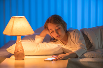 The girl lay on the bed and phone. Evening night time