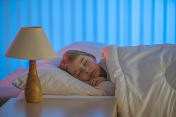 The young girl sleeping on the bed. Evening night time