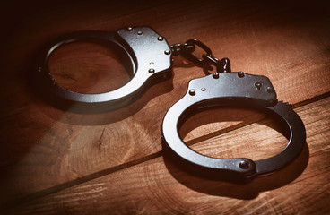 black metal handcuffs on wooden background