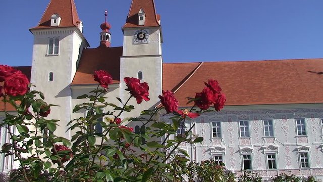 Rote Rosen im Vordergrund veredeln die Ansicht auf die Kircht&uuml;rme und Fassade des Stiftes Vorau