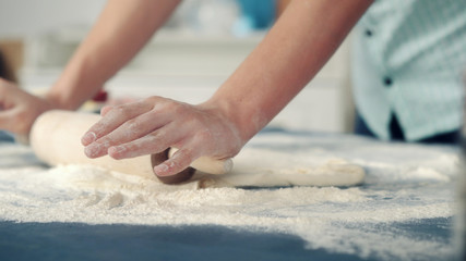 Hands chefs in flour roll the dough