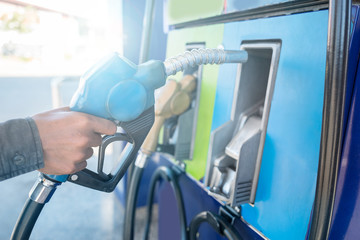 Close up of man's hand holding fuel pump and refueling car in Gas station