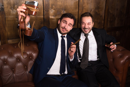 Rich businessmen with cigars making photos while spending time in restaurant. Russian business people drinking alcohol and making money.