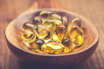 Cod liver oil on wooden spoon. Health care concept