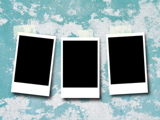 Three blank black rectangular photo frames hanged by pegs against blue scratched wall