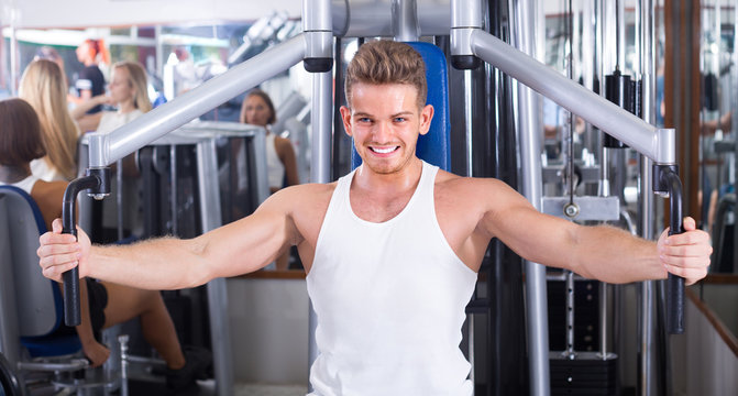 Young man using fly machine in gym.