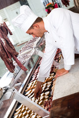 Seller in working clothes taking raw meat