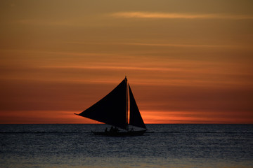 Fototapeta na wymiar Lonely sailboat at sunset background over the sea in Boracay Island, Philippines
